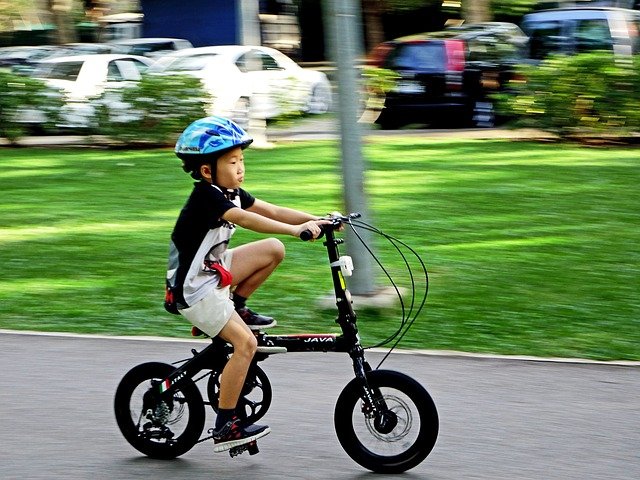 A young child riding on the back of a bicycle