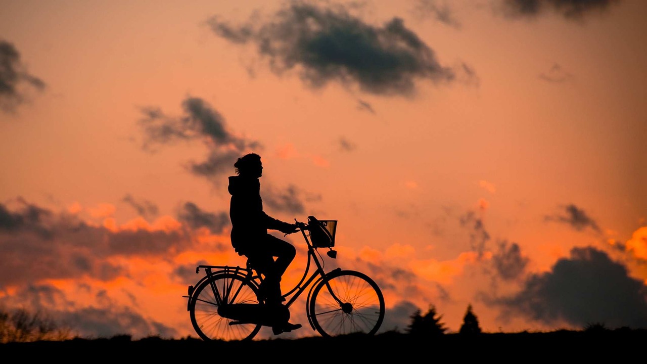 A person riding a bicycle with a sunset in the background